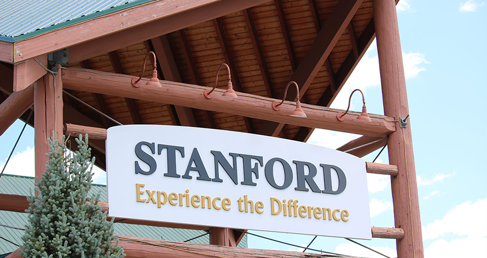 A view of the triangular shaped roof of the portico at the front entrance to Stanford Fernie Resort, bearing a large white rectanguar sign with the corporate name in black lettering and slogan in yellow lettering.
