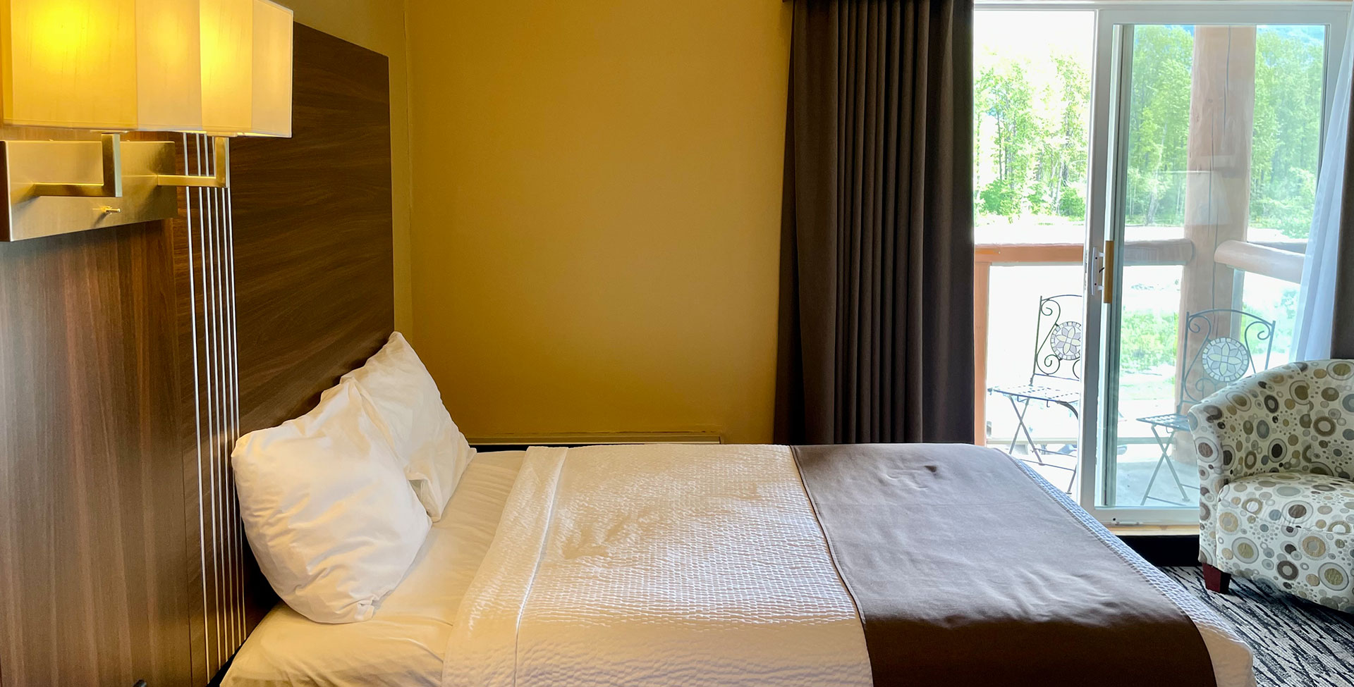 In a peaceful corner in a suite at Stanford Fernie Resort with a moss green armchair set before a coffee table with an open bottle of wine and two filled wine glasses and a plate of green grapes.  